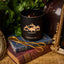 Black candle labeled 'Black Hills Candle Calamity Jane' on a stack of books with decorative items.
