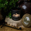 Black candle with 'Black Hills Candle' logo on a lace doily with decorative elements.