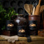 Ceramic containers with wooden spoons and a decorative mat on a rustic surface.