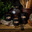 Black candles with 'Black Hills Candle' branding on a rustic wooden surface with a teapot and utensils.