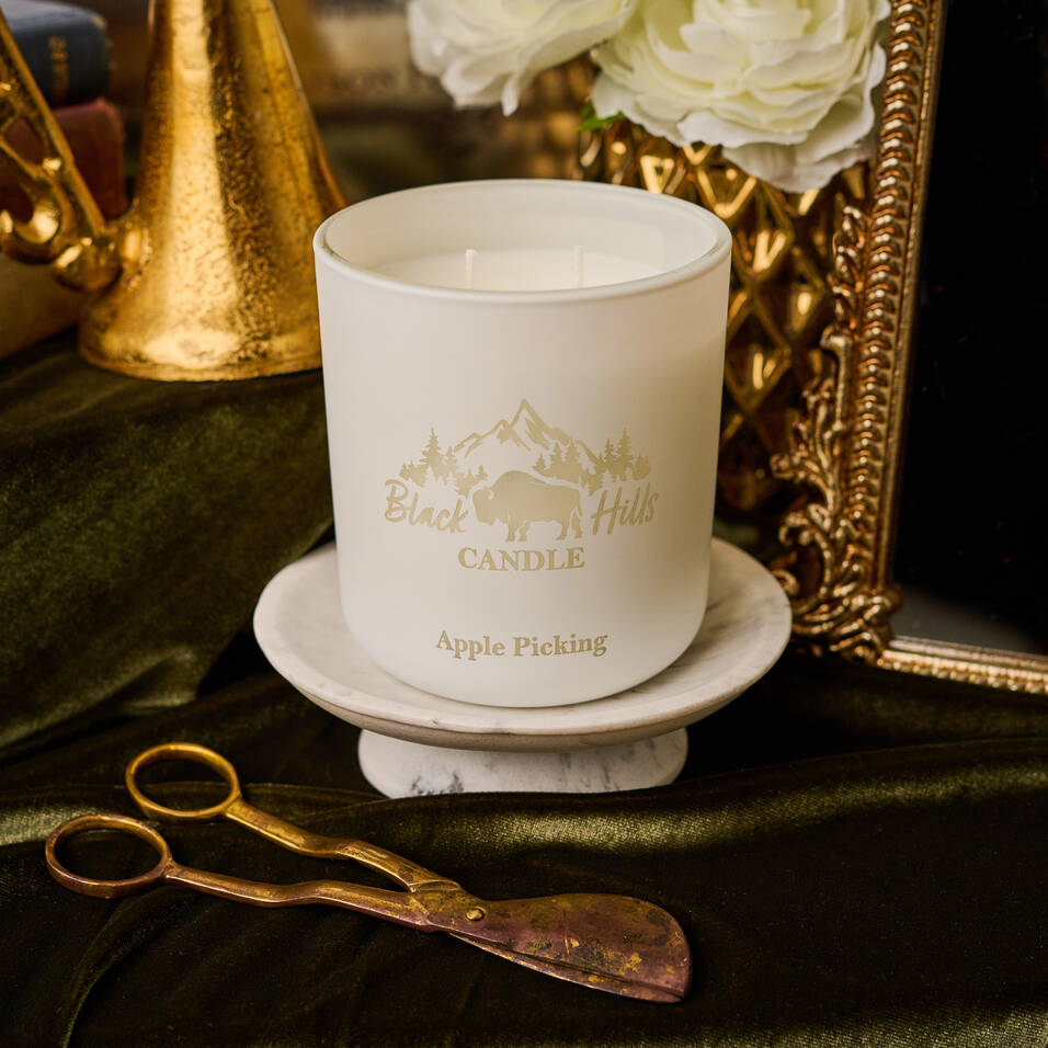 Candle on a table, laying next to wick cutters