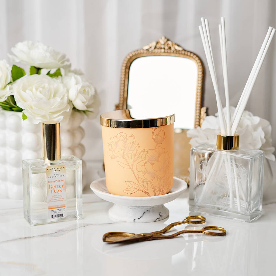 Decorative items including a candle, diffuser, and flowers on a white surface.