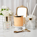 Decorative items including a candle, diffuser, and flowers on a white surface.