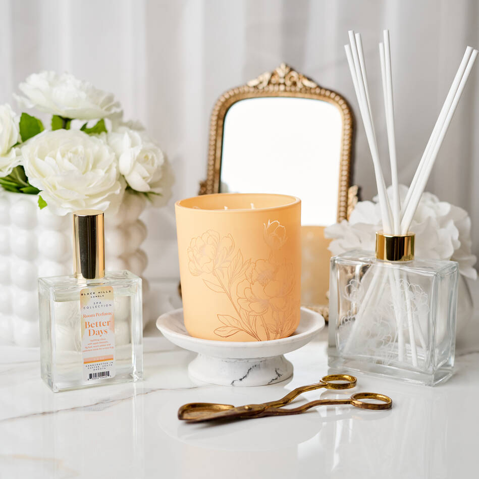Decorative items including a candle, diffuser, and flowers on a white surface.