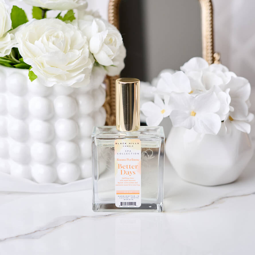Perfume bottle labeled 'Better Days' with white flowers in the background