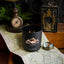Black candle with 'Black Hills Candle' branding on a map with vintage items around