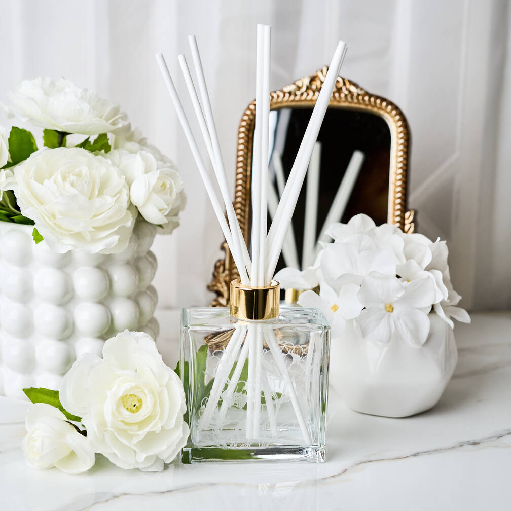 Diffuser with reeds and decorative flowers on a marble surface Main image