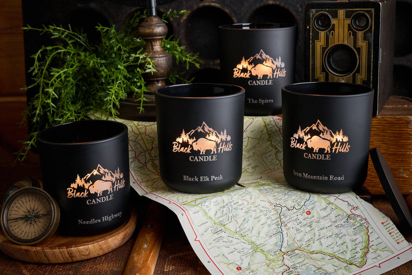 Black candles with mountain design on a wooden surface with a map Main image