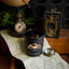 Black candle with 'Black Hills Candle' logo on a map with vintage items around