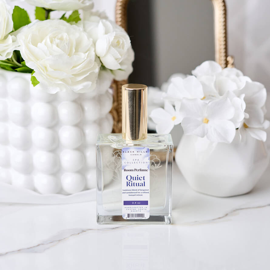 Room perfume bottle labeled 'Quiet Ritual' with white flowers in the background