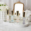 Collection of perfume bottles on a tray with a decorative mirror and flowers in the background