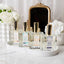 Collection of perfume bottles on a white surface with flowers and a mirror in the background