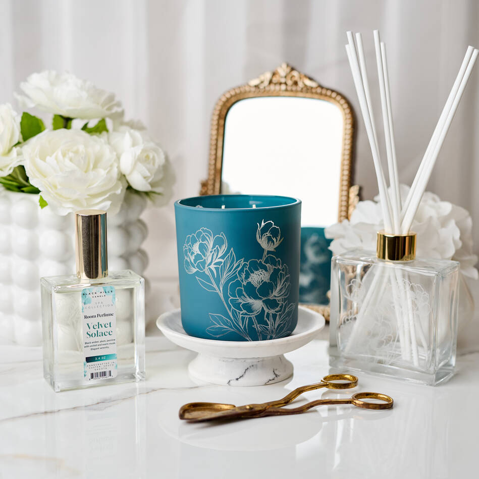 Decorative items including a blue candle, diffuser, and flowers on a white surface.