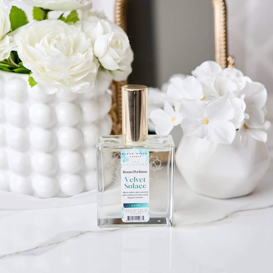 Perfume bottle labeled 'Velvet Solace' with white flowers in the background